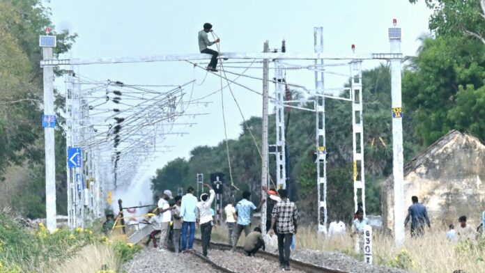 Railway workers working to restore the overhead equipment which was damaged after a pantograph of a speeding train hit it near Uchipuli in Ramanathapuram district on October 14, 2025